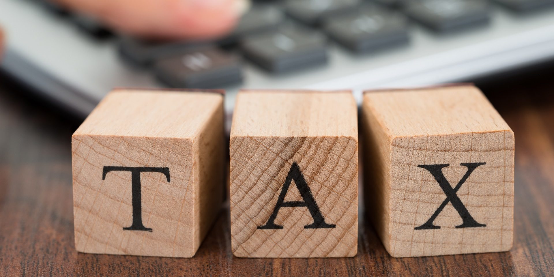 Person Hand Using Calculator With Tax Word On Blocks Disclosure of business tax debts